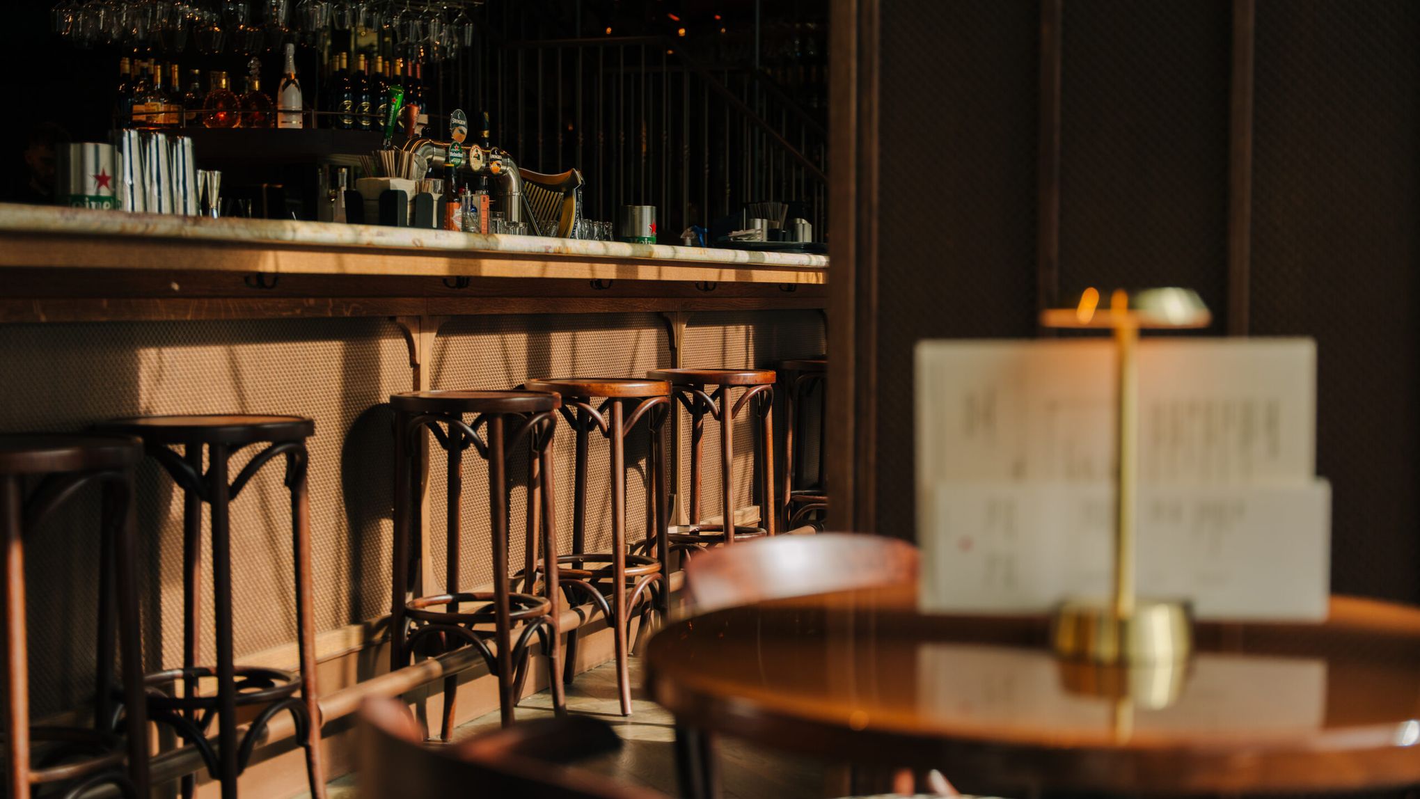 The bar with wooden bar stools, a brass table lamp in the foreground